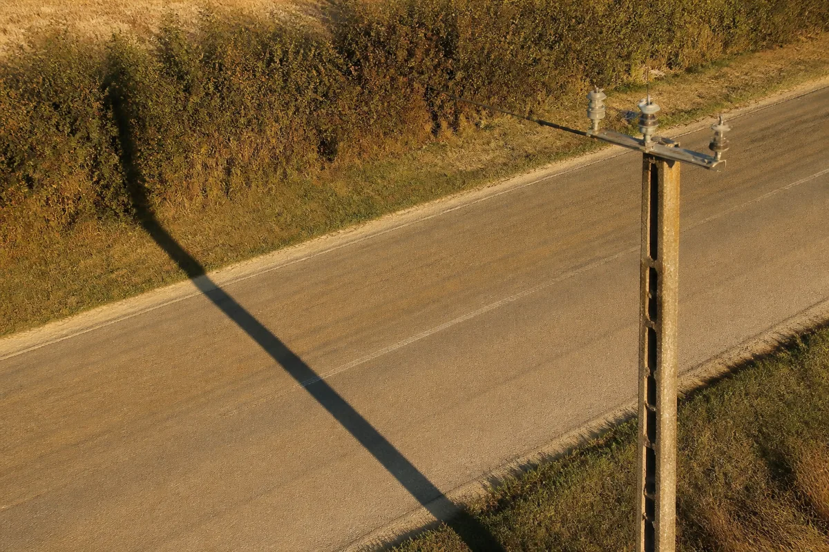 Ombre allongée d&rsquo;un poteau électrique projetée sur une chaussée