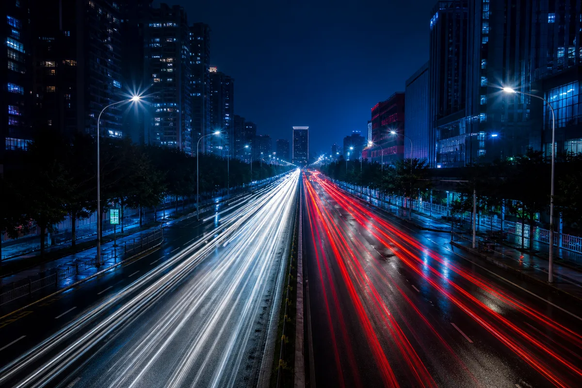 Traînées lumineuses de circulation sur un boulevard urbain photographié en pose longue depuis un pont